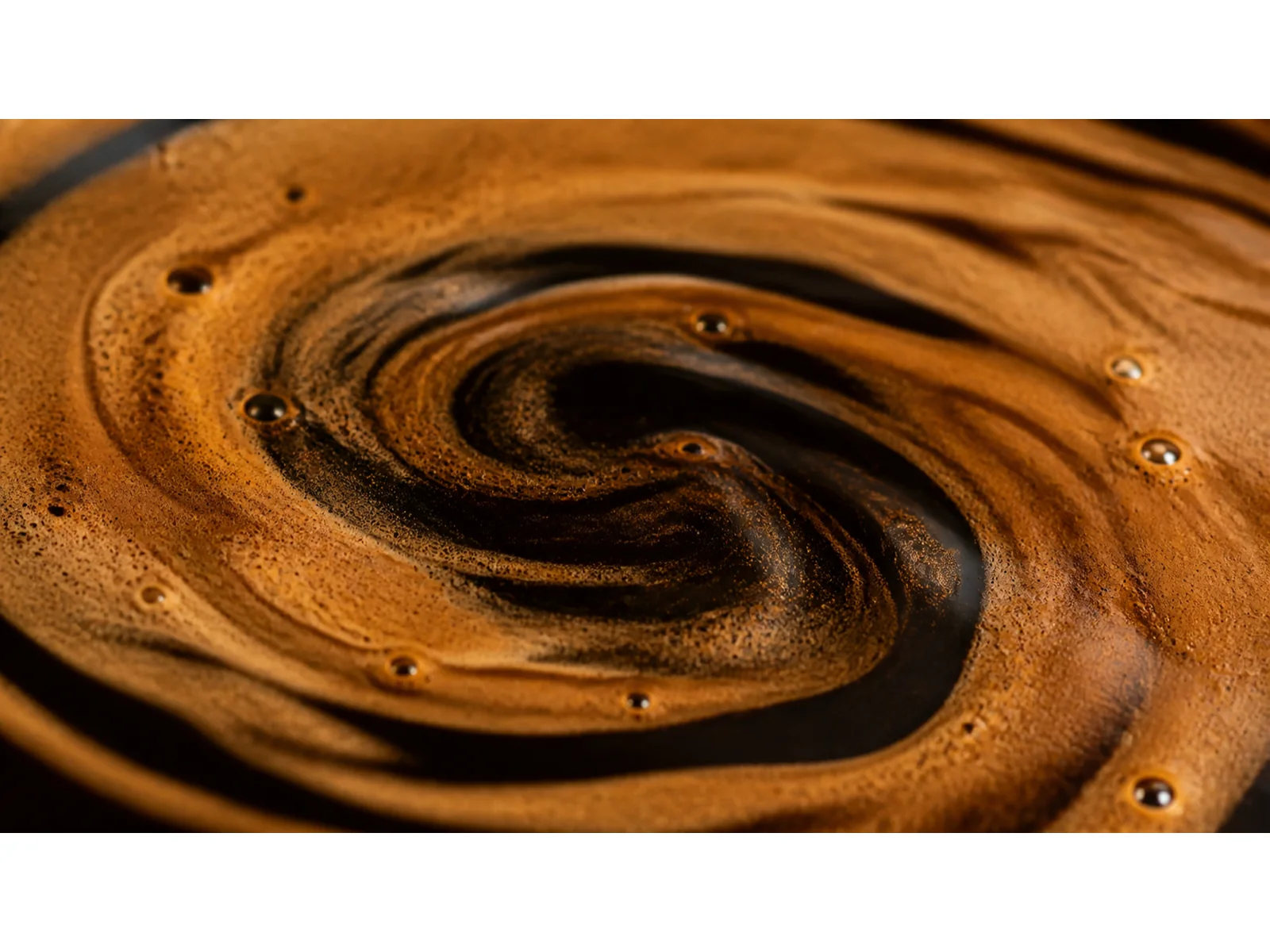 Abstract espresso-crema texture in warm brown and near-black tones.