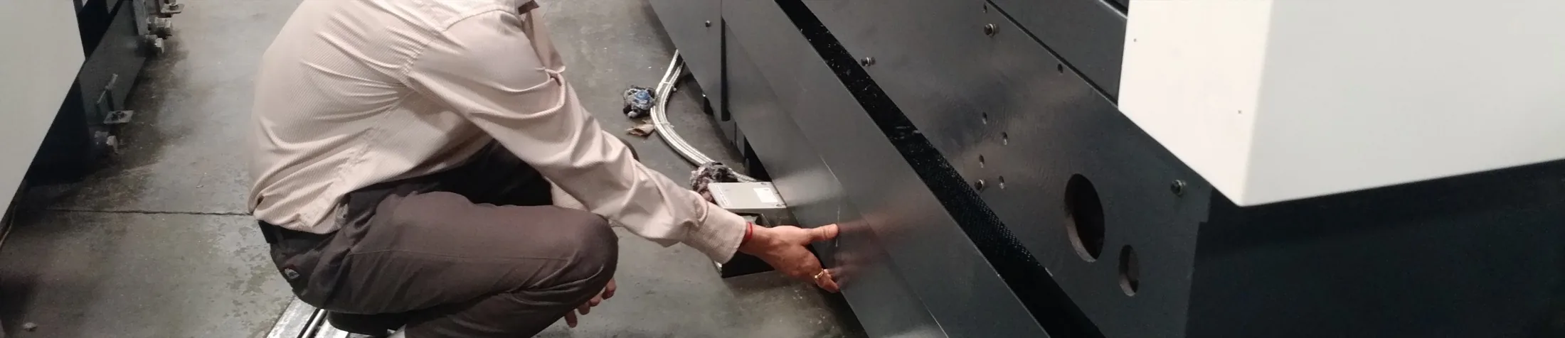 Privacy-safe crop of a person squatting and reaching toward a low front service panel.