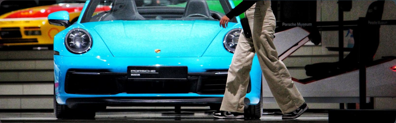 A bright blue sports car photographed as pedestrians pass by.